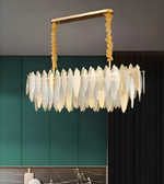 Luxury chandelier with gold frame and white glass shades against a green wall.