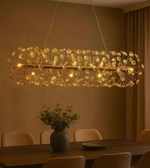 Modern chandelier hanging above a dining table with chairs and a vase of flowers.