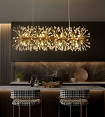 Modern chandelier hanging above a kitchen counter with stools.