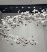Artistic installation of white and brown birds on a ceiling