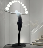 Modern sculpture of a woman with a circular light fixture above her head in an indoor setting.