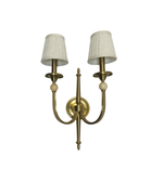 Brass wall sconce with two white lampshades on a white background