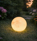 Glowing spherical outdoor light in a garden setting with flowers and grass.