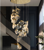 Modern chandelier hanging in a room with dark walls and a plant.