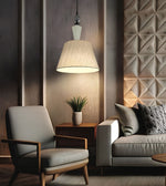 A modern living room scene featuring a lit pendant lamp with a textured beige drum shade hanging over a mid-century modern armchair next to a light gray sofa with patterned pillows.