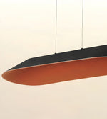 A modern pendant light with a curved, elongated design, featuring a matte black top surface and a terracotta orange underside, suspended by thin cables against a plain off-white background.