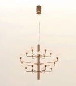 A modern multi-light chandelier with a brushed brass finish and glowing frosted glass globe bulbs, suspended against a plain off-white background.