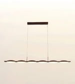 A modern linear chandelier with six illuminated oval light heads and a dark metal frame, suspended by two thin cables from a rectangular ceiling mount against a plain off-white background.