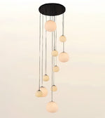 A modern multi-light pendant chandelier with a black circular ceiling canopy and multiple hanging frosted glass globes of varying sizes, shown against a plain light background.