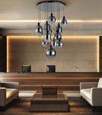 A modern multi-light chandelier with reflective silver glass globes hanging in a lobby setting with a reception desk and beige seating.