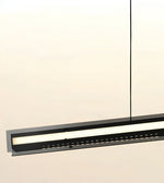 A modern linear LED pendant light fixture in matte black, suspended by a thin vertical cord against a warm off-white background.