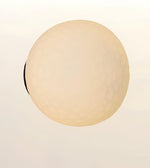 A spherical, textured light fixture or lamp shade in a warm cream or beige color, shown against a plain off-white background.