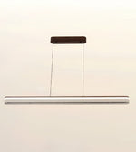 A modern linear LED pendant light with a slim silver-white bar, suspended by two thin cables from a dark brown rectangular ceiling mount against a plain off-white background.
