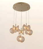 Modern multi-light pendant ceiling fixture with a round brushed brass canopy and five faceted glass globes glowing with warm light, shown against a plain off-white background.