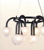 Modern multi-light chandelier with a matte black curved metal frame and frosted white glass shades, shown illuminated against a plain light background.