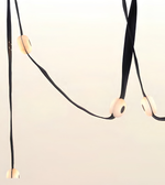 A minimalist black cord pendant light with smooth, rounded off-white wooden beads spaced along the cord, photographed against a clean, light off-white background.