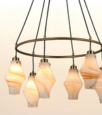 Modern circular ring chandelier featuring multiple marble-effect glass pendant lights with brushed brass accents and warm ambient illumination.