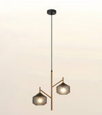 A modern two-light pendant ceiling fixture with a black canopy and cord, a central vertical rod, and two angled arms holding textured gray glass shades, shown against a plain light background.