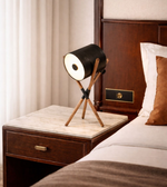 Industrial-style tripod table lamp placed on bedside table in contemporary bedroom interior
