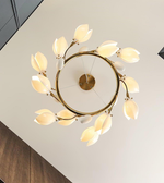 Modern ceiling light fixture with gold frame and white leaf-shaped lights on a neutral background