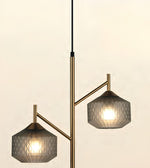 Modern two-light pendant lamp with a brushed brass/gold branch-like metal frame and textured gray glass shades, shown against a plain light beige background.