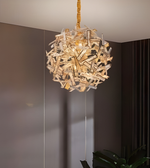 Decorative chandelier hanging in a room with a neutral wall and plant.