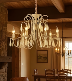Chandelier hanging in a warmly lit room with wooden furniture and stone wall.