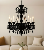 Black chandelier with candles on a wall above a beige sofa.