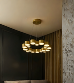 Gold chandelier hanging in a room with a black wall and patterned curtain.