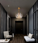 Modern hallway with a decorative chandelier, white armchair, and dark walls.