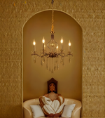 Chandelier hanging above a sofa with cushions in a room with textured walls.