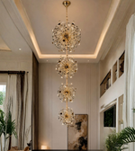 Modern chandelier hanging in a stylish living room with plants and artwork.