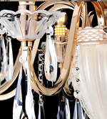 Close-up of the chandelier's decorative gold arm, central structure, and hanging crystal-style ornaments.