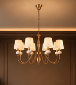 Detailed view of ivory pleated chandelier shades, decorative ribbed accents, and polished gold-tone metal fittings.
Copy alt text