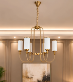 Close-up of a luxury gold chandelier featuring six white cylindrical glass shades, curved metal arms, and a tall central frame.