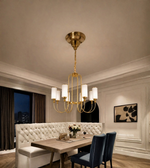 Gold EIGHT-light chandelier with white cylindrical shades suspended above a dining table in an elegant interior.