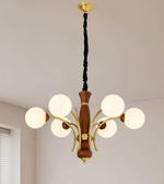 A 6-light chandelier with a warm brown wood central column, gold-finished metal arms, and six white spherical glass shades, suspended by a black cord from a gold ceiling canopy in an indoor room.