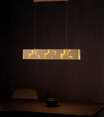 Geometric linear LED pendant light with warm illumination above a dining table in a modern interior