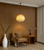 Modern living room with a pendant light, armchair, and decorative items.