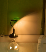 Vintage green banker lamp casting warm light on desk surface