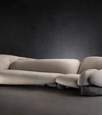 Modern beige sectional sofa with sculptural design against a dark background
