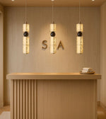 Modern spa reception with pendant lights, wooden desk, and rolled towels on a tray