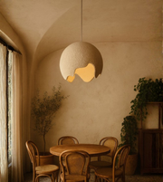 Sculpted globe pendant light illuminating a minimalist natural dining area