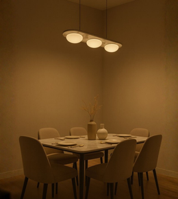 Three-dome frosted glass pendant light suspended above an elegant dining table with beige seating