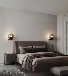 Smoked glass globe wall light mounted beside a modern upholstered bed in warm neutral bedroom interior