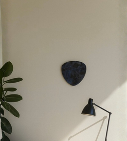 Dark sculptural wall light with stone-like texture mounted on minimalist wall.
