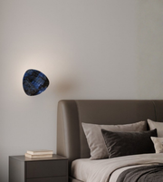Textured triangular wall light with matte stone finish. Adds subtle artistic character to minimal, modern interiors.