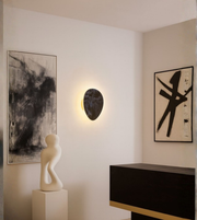 Textured triangular wall light with matte stone finish. Adds subtle artistic character to minimal, modern interiors.