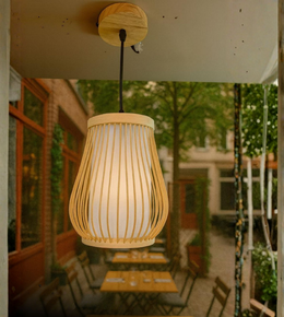 Natural bamboo barrel-shaped hanging lamp with frosted diffuser in a cozy café setting.