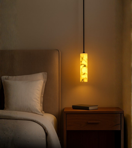 Soft glowing cylinder pendant used as bedside lighting in a modern room